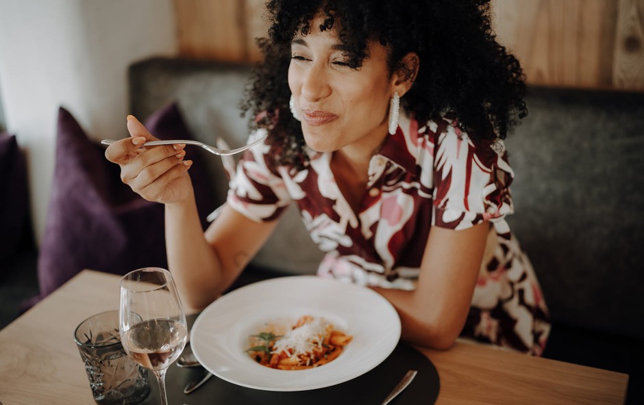 Frau genie&szlig;t das Abendessen im Dorfer-Restaurant