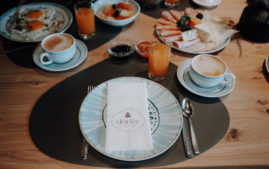 Ein reichhaltiges Fr&uuml;hst&uuml;ck mit Kaffee, Saft, Spiegelei und Brotaufstrichen auf einem Holztisch